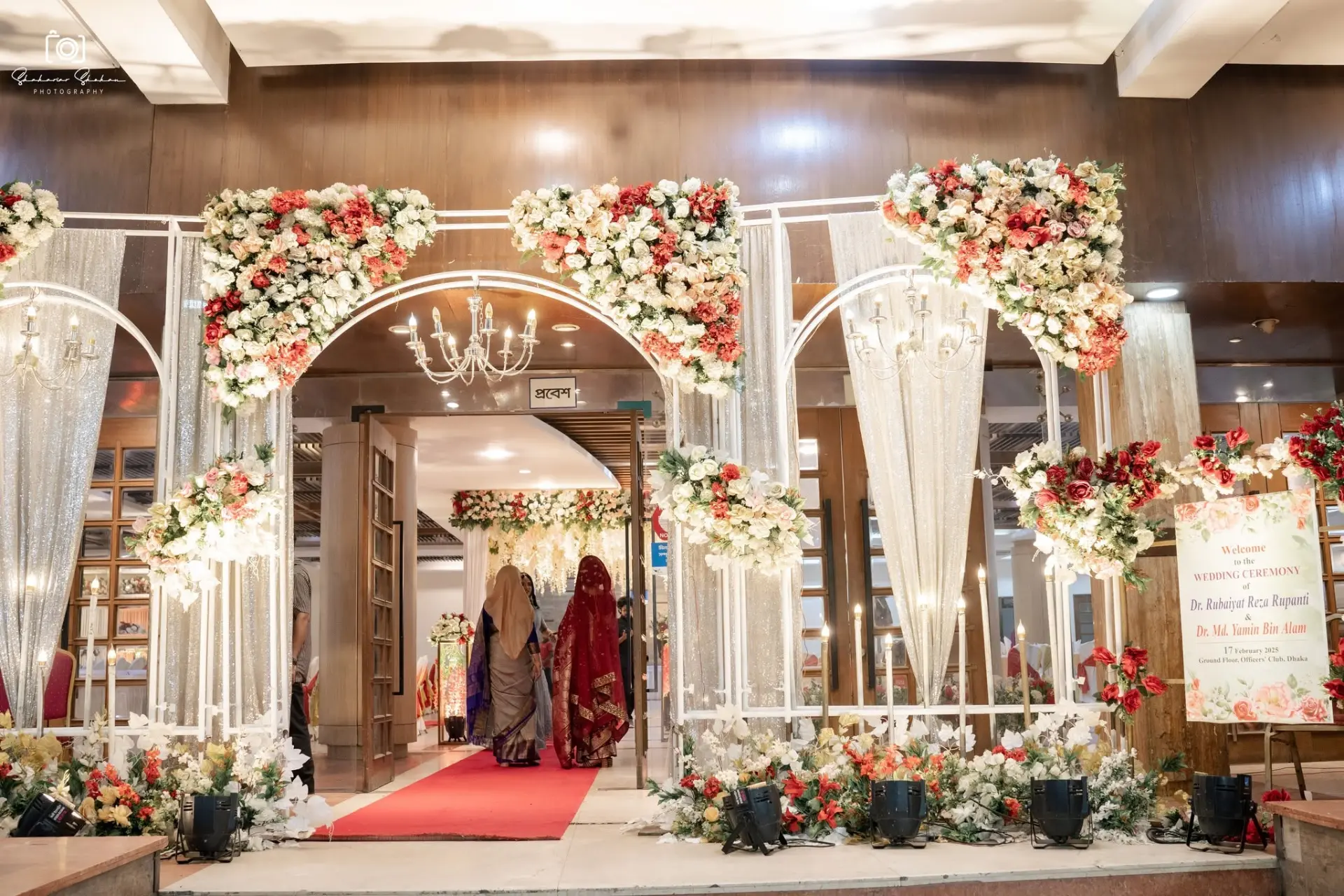 Floral wedding entrance gate with chandeliers and welcome board