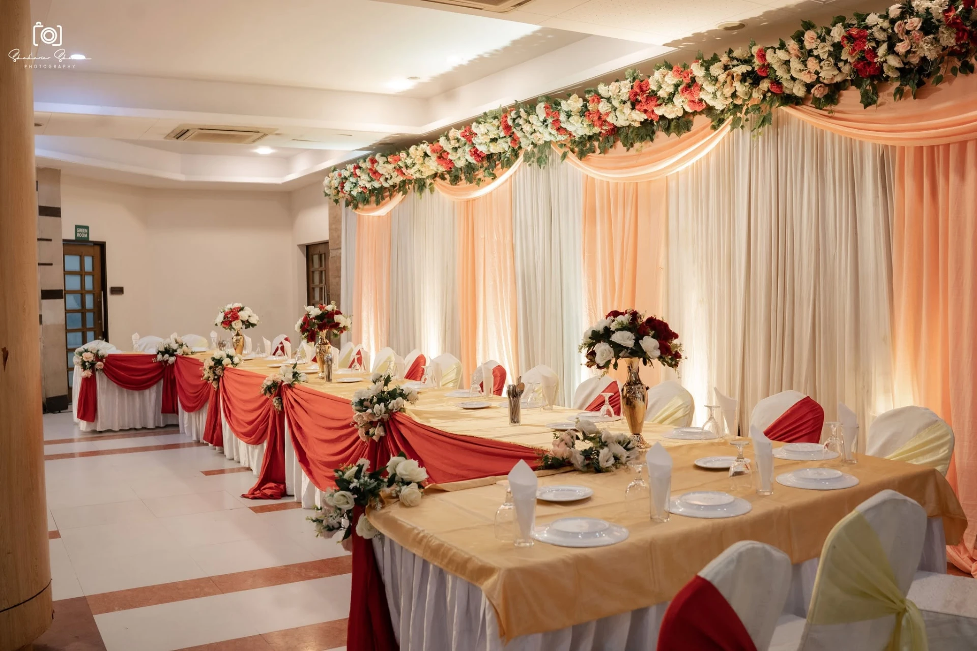 Guest dining tables with gold and red drapes and floral centerpieces