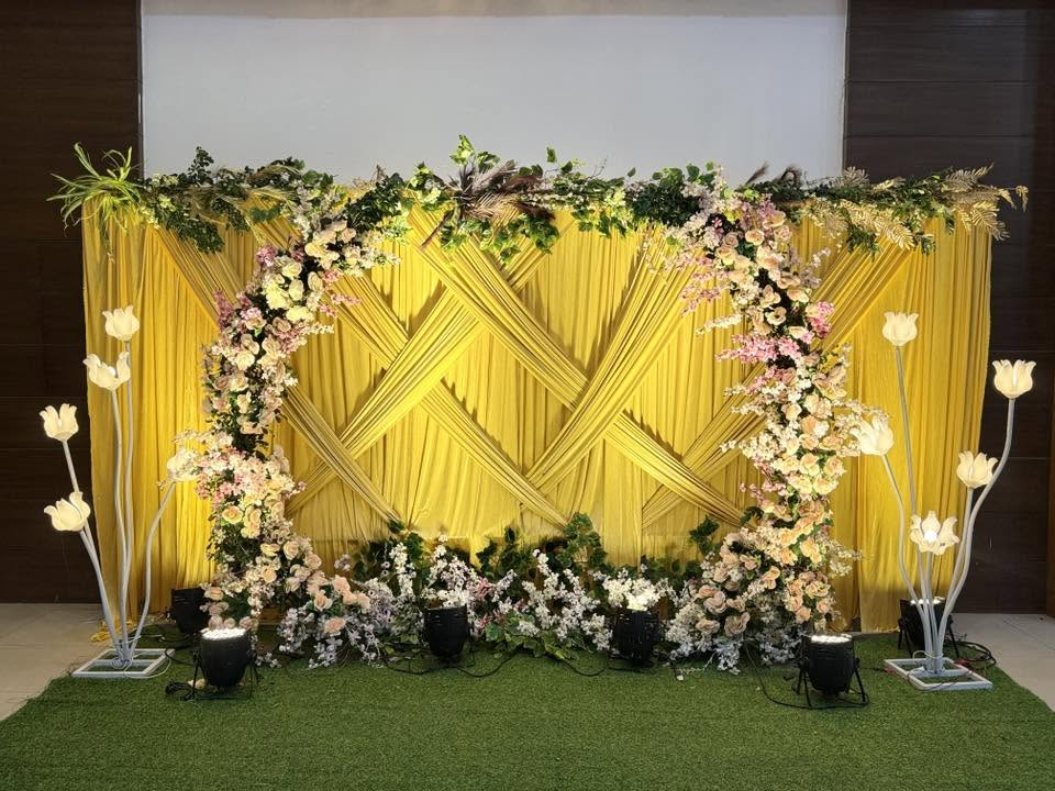 Yellow draped photo backdrop with floral arch