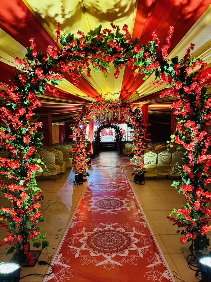 Red floral archway walkway leading to wedding stage