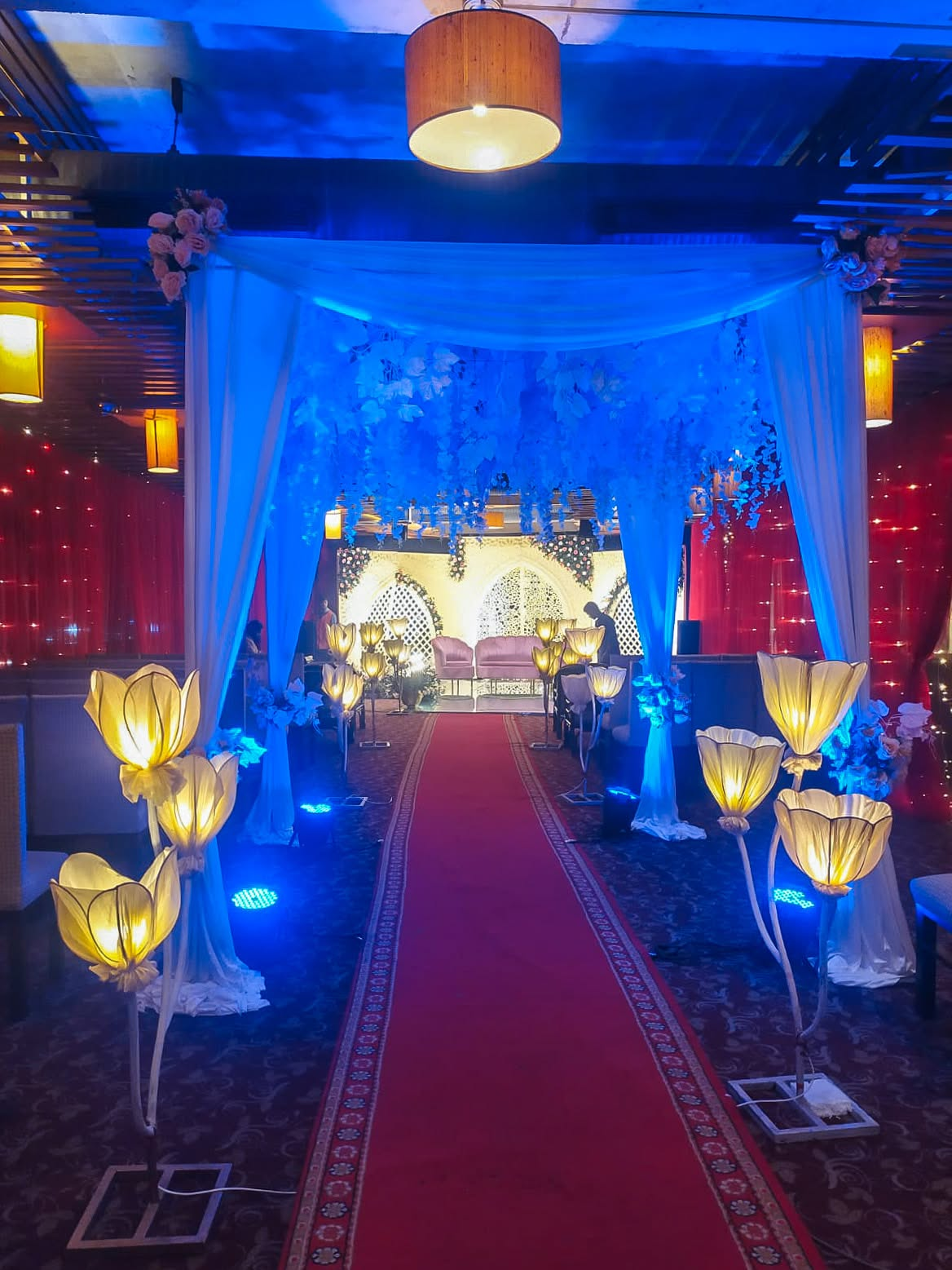 Blue lit canopy walkway leading to the wedding stage