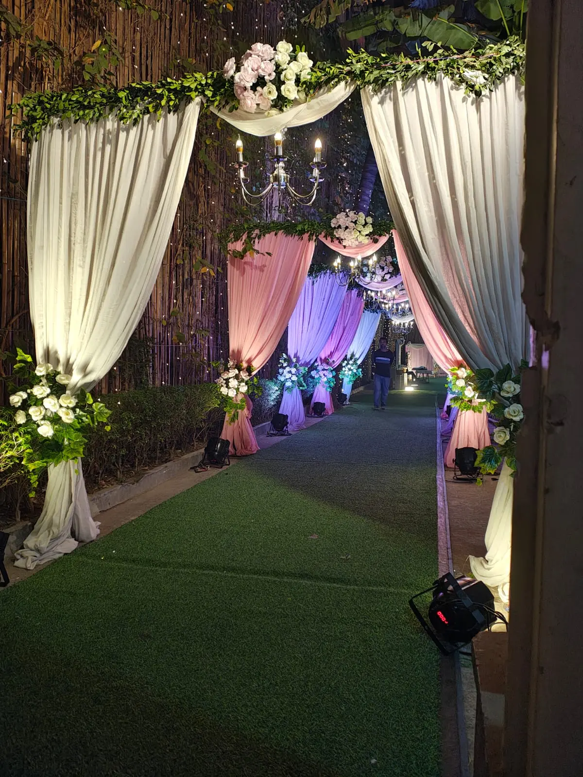 Draped walkway with chandeliers and florals