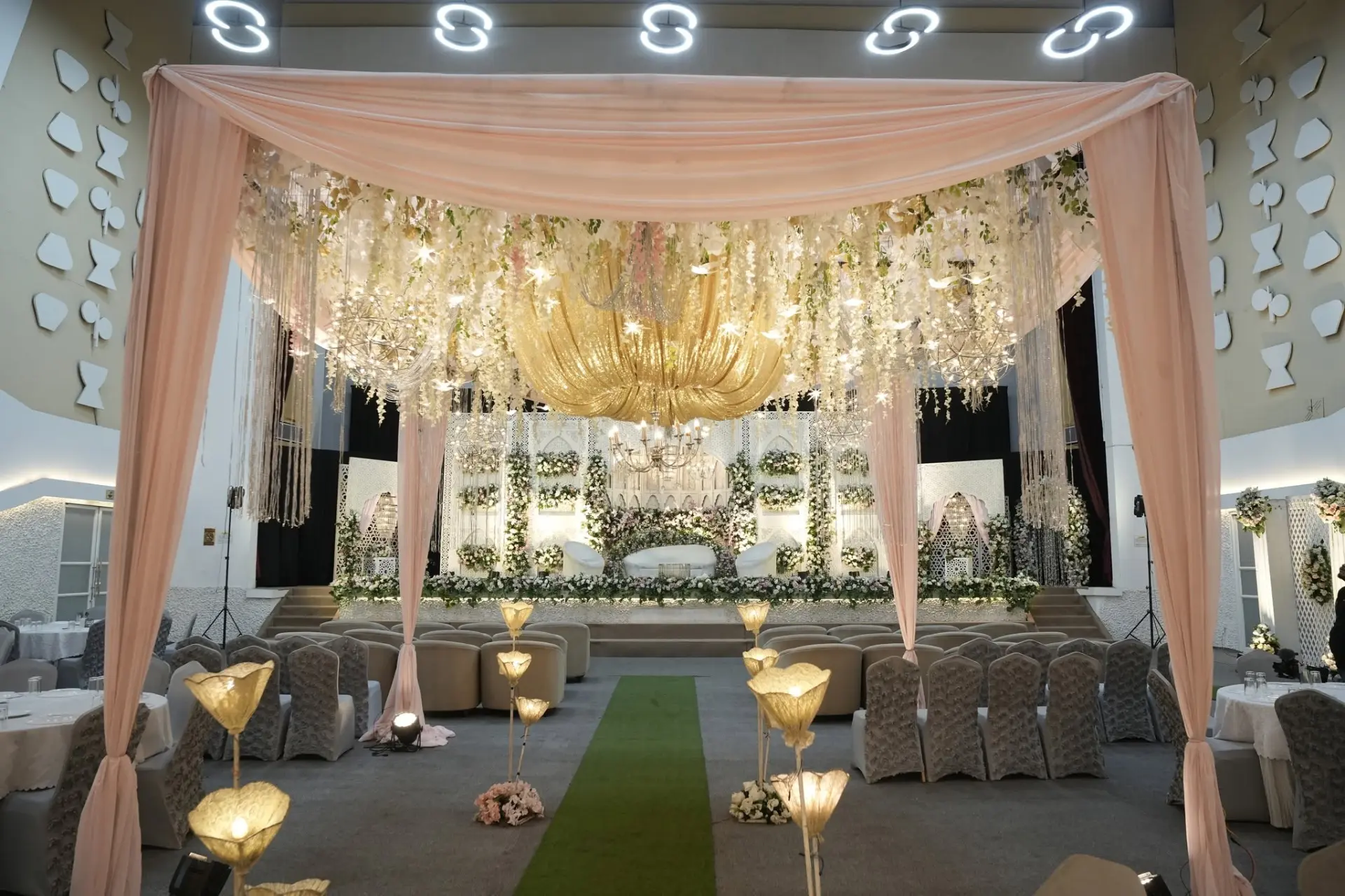 Blush draped canopy walkway with gold chandelier