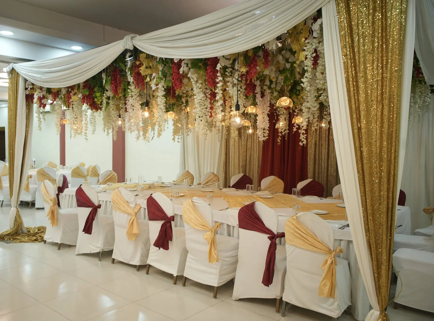 Gold and maroon draped dining canopy with hanging florals