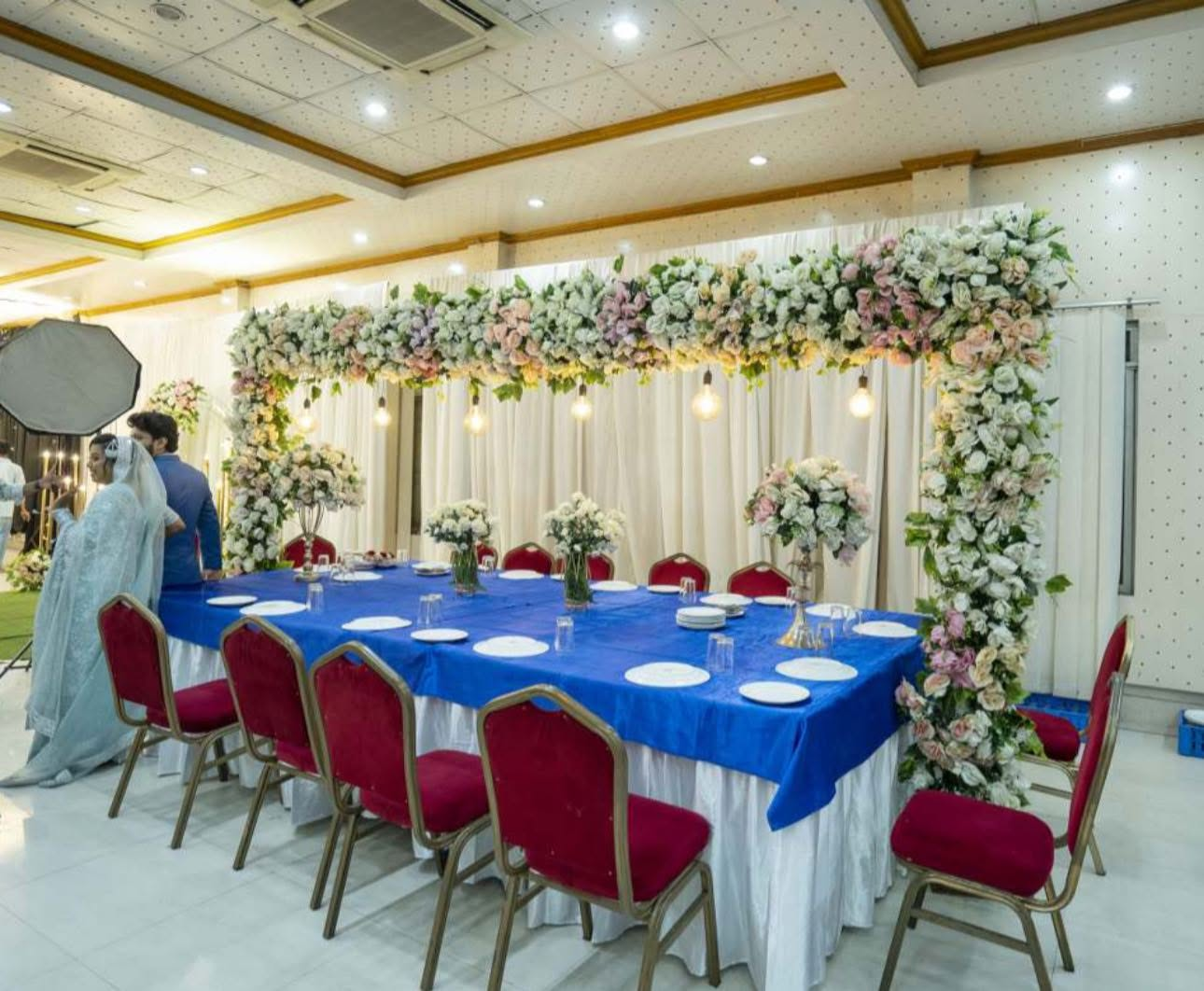 Family dining table under a floral canopy with edison bulbs